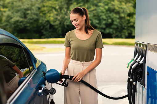 Smiling Woman Refilling Auto with Bio Fuel at Modern Petrol Station Outdoor, Enjoying Refueling Experience. Eco Friendly and Convenient Car Care, Automobile Fueling Offer Concept