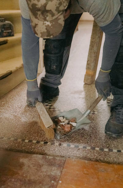 A young man holds a bag of construction waste indoors.