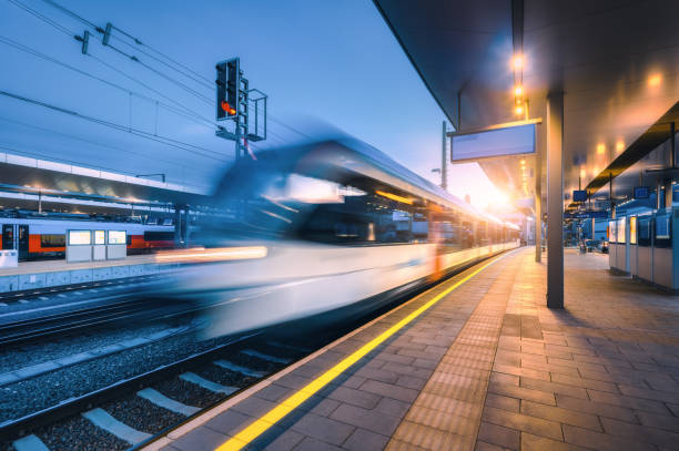 istock Blurred high speed train on the modern railway station at night in Graz, Austria. Fast moving intercity passenger train on the railway platform at sunset. Railroad. Passenger railway transportation 1789007172