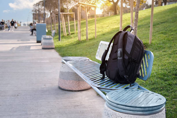 A lost or forgotten backpack on bench in a city park.