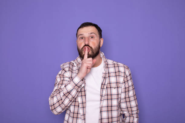 istock Serious good looking bearded male, keeps fore finger on lips, tries to keep conspiracy. 1789044162