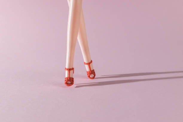 istock Walking female doll legs in bright light on pink background. 1789051204