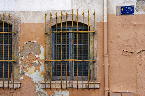 Windows with metal grid and weathered facade at City of Toulon on a cloudy late spring day. Photo taken June 9th, 2023, Toulon, France.