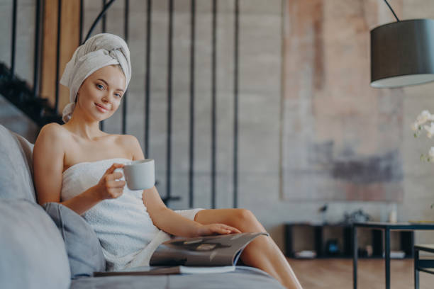 istock Content woman sips coffee on sofa, wrapped in a towel, relaxing indoors 1789056030