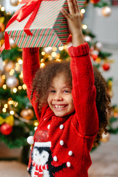 istock A Black girl holds a Christmas gift over her head 1789056662