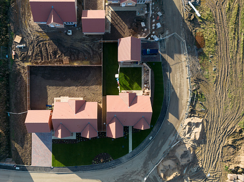 Drone top down view of newly built retirement bungalows seen on a busy housing development site in the UK. One bungalow is seen occupied by new owners.