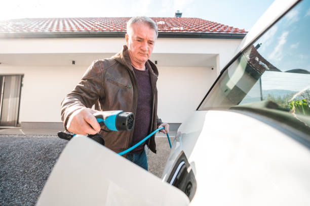 istock Senior Man Using his Electric Plug to Charge a White Car 1789103054