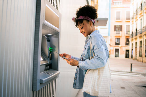 happy young woman on vacation using the atm - bankväsen bildbanksfoton och bilder