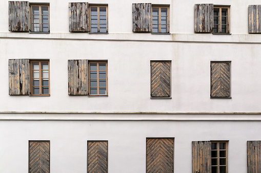 white building wall with arches and wooden shutters in a horizontal pattern