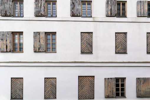 A white building wall with many horizontal windows and wooden shutters on it