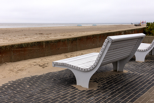A white wooden bench on the shore of the beach with a view of the sea