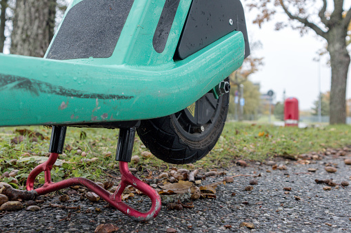 A green bicycle-scooter placed on its leg in the stop position