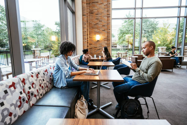 istock Curly multiracial student using laptop in the lobby, talking to Latino friend 1789126878