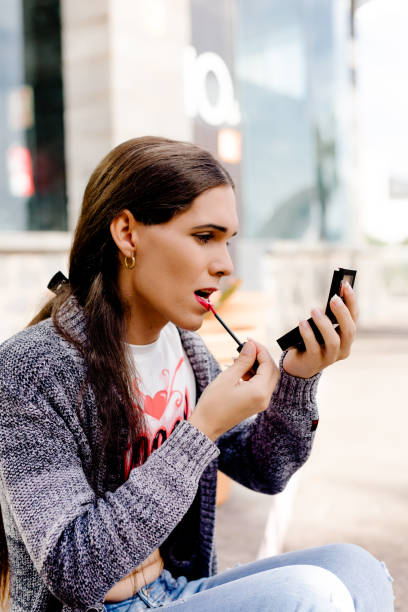 istock Transgender woman applying lip gloss while doing makeup 1789152559