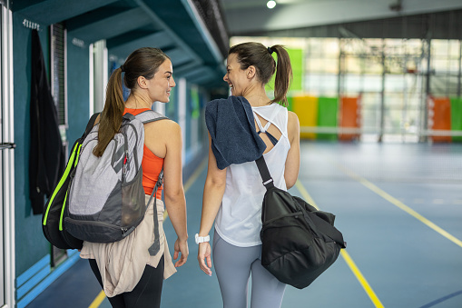 Back view of two young women entering the sports hall ready for the training
