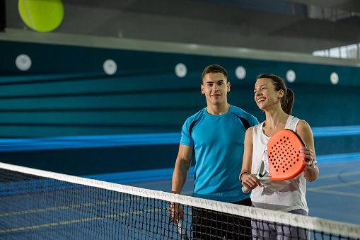 Young couple discussing  paddle tennis techniques on indoor court
