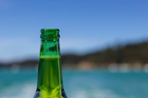 Beer bottle top with an ocean background, freshly opened with the hops bubbling at the surface. Ideal background for boaties.