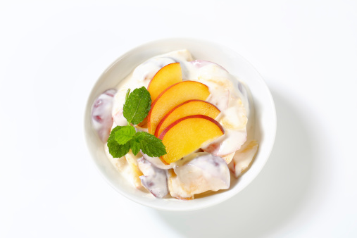 peach slices with yoghurt dressing in white bowl
