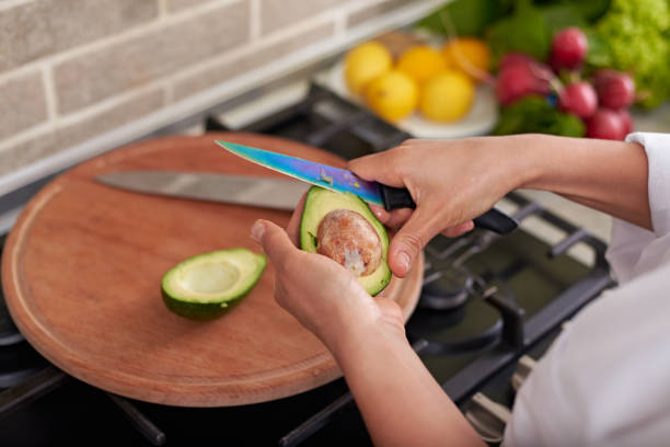istock Woman's hands holding an avocado fruit and peeling it while standing at the kitchen counter, preparing healthy salad 1789160120