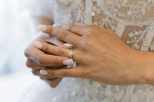 A lovely bride wearing a white gown stands hand in hand with her partner on her wedding day