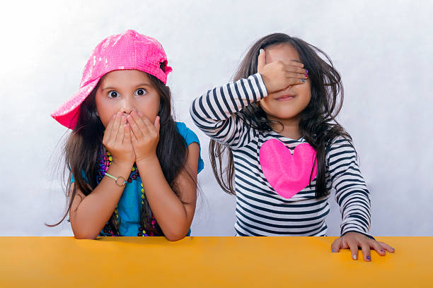 A family portrait of two Hawaiian preteen girls standing and comparing height, growing up in childhood. Photographed on white background.
