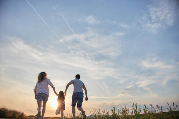 Young mother, father and daughter in field on a sunset.