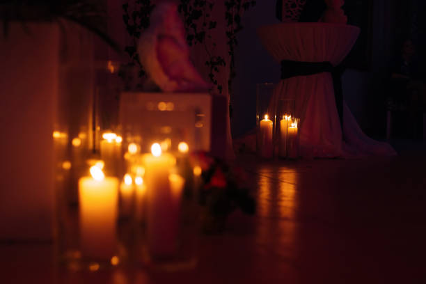 high candles in glass flasks in a dark room. Round table with a tablecloth and a ribbon