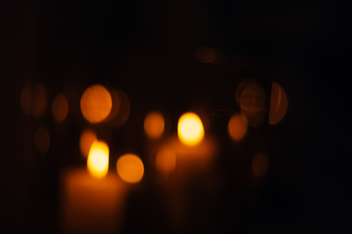 blurred silhouettes of candles that burn in a dark room