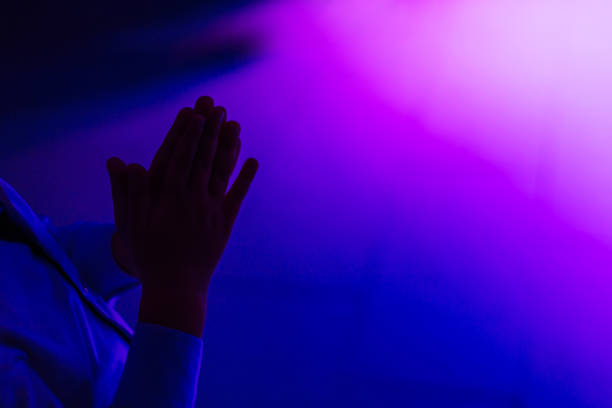 Dark silhouette of female hand holding a large industrial hex nut fastener and making the OK hand sign gesture - Body language, shadow and outline and human communication concept