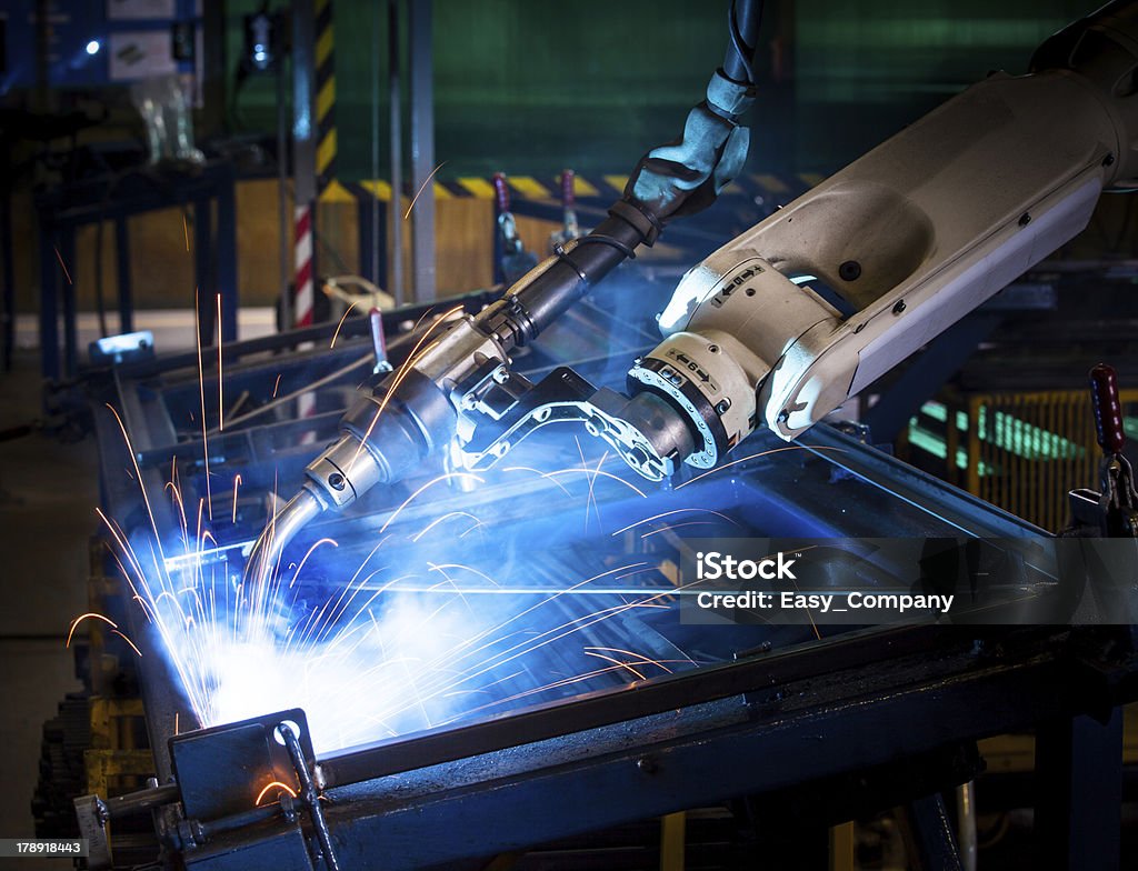Robotic arm welding. Robot arm welding uses torch to make sparks during manufacture of metal equipment. Machinery Stock Photo