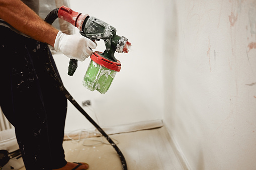 Painter hold green spray gun close up.