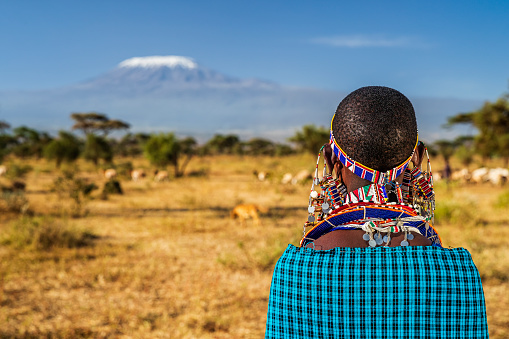 African woman from Masai tribe looking at Mount Kilimanjaro, Kenya, Africa. Maasai tribe inhabiting southern Kenya and northern Tanzania, and they are related to the Samburu.
