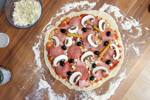 selbstgemachte und selbstbelegte Pizza wird auf einem Pizzastein am Grill gebacken