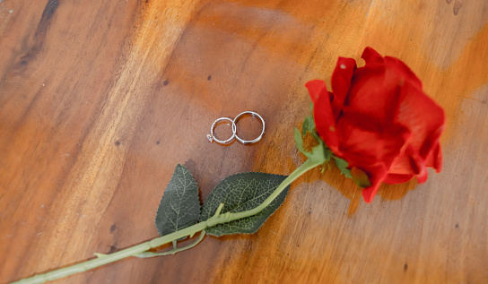 couple rings and roses on wooden table