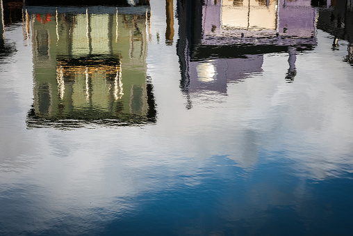 Colorful, purple and green painted and restored houseboats are reflected in the still water of Richardson Bay in Sausalito, California.