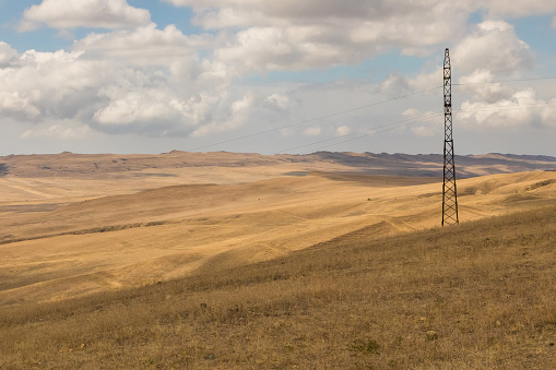 Landscape of the Georgian steppe Udabno in Georgia. Yellow-gold grass, wilde land and blue sky. Endless fields. Mountain in the background.