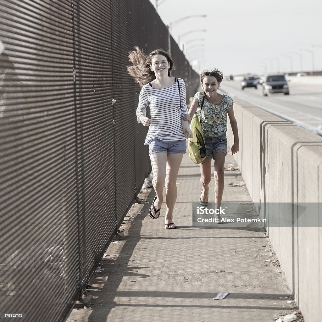 Duas meninas andando sobre uma ponte na zona industrial - Foto de stock de 12-13 Anos royalty-free