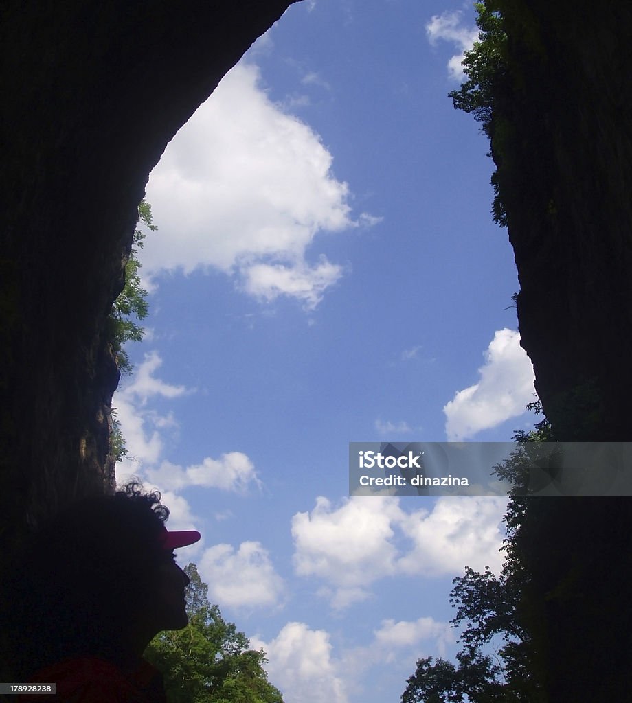 Natural keyhole A silhouetted person views blue sky and clouds within a natural stone formation in the U.S. Blue Ridge mountains. Appalachia Stock Photo