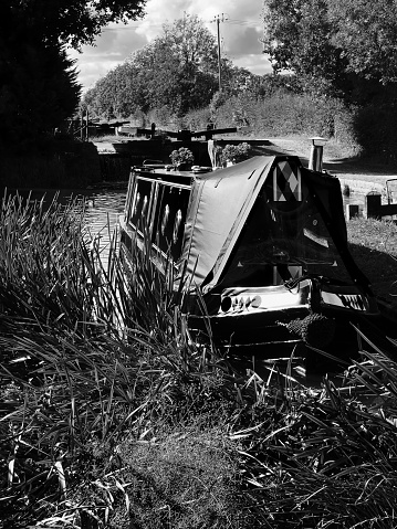 This is a narrow boat houseboat barge moored on the canal waterway Worcestershire, England, UK. It is a warm sunny day in early spring and there are no visible people in the picture. The hire boats have all been painted in preparation for the summer when tourists hire them.