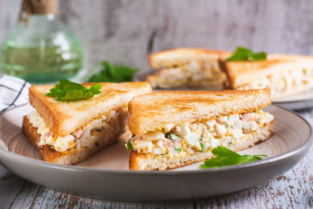 istock Chopped sandwiches with egg, bacon and herbs salad on a plate on the table 1789304025