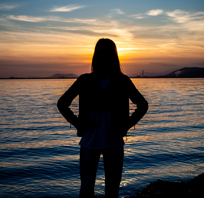A beautiful girl sitting at a boat in the beach in Mallorca during the sunset