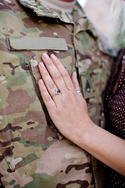 Soldier wife's hand Spouse touches soldier's chest. Soldier's uniform represents deployment due to the multicam pattern. military deployment photos stock pictures, royalty-free photos & images