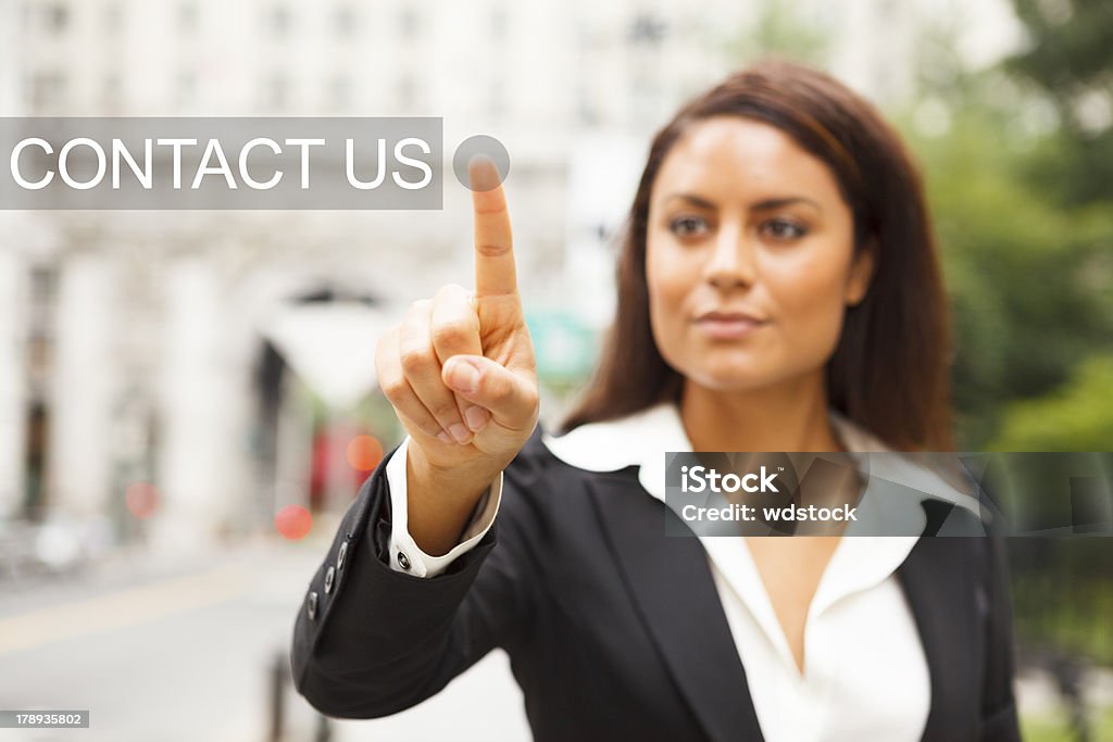 Young Woman Presses CONTACT US Button A young well dressed woman on a city street presses a virtual CONTACT US button suspended in mid-air. A Helping Hand Stock Photo