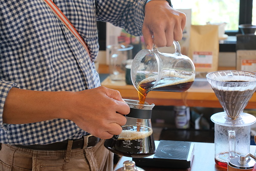 A barista brewing a cup of coffee using pour over method, Cooking delicious and aromatic coffee in North of thailand.