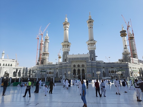 A beautiful daytime view of Babe Fahad and pilgrims in the outer courtyard of Masjid Al Haram in Mecca, Saudi Arabia.