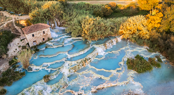 Most famous natural thermal hot spings pools in Tuscany -  scenic Terme di Mulino vecchio ( Thermals of Old Windmill) in Grosseto province. Aerial drone view
