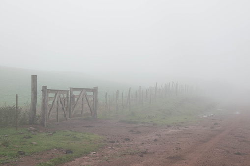 Foggy morning in the countryside with wooden gate in the foreground