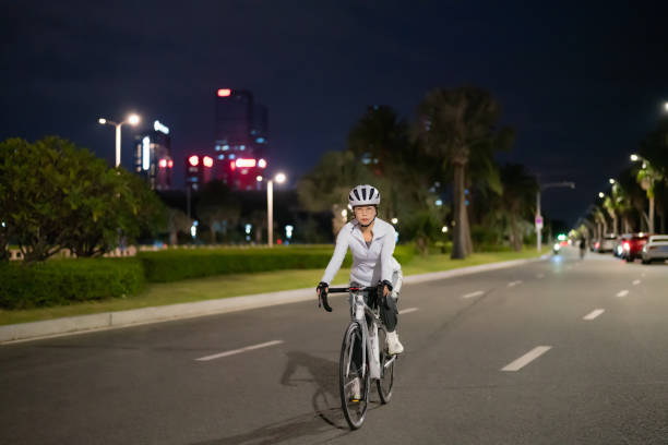 femme asiatique faisant du vélo de route la nuit - mental health women asian ethnicity bicycle photos et images de collection