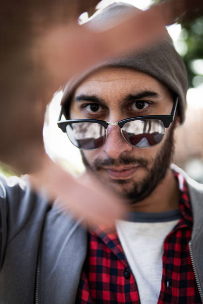 Urbanite in shades, hand blurred, sunlight play, close-up portrait in Madrid.