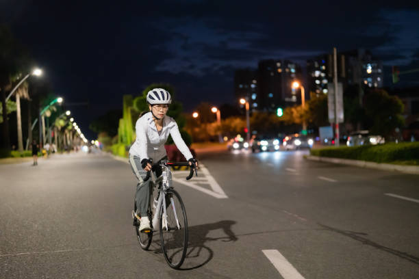 femme asiatique faisant du vélo de route la nuit - mental health women asian ethnicity bicycle photos et images de collection